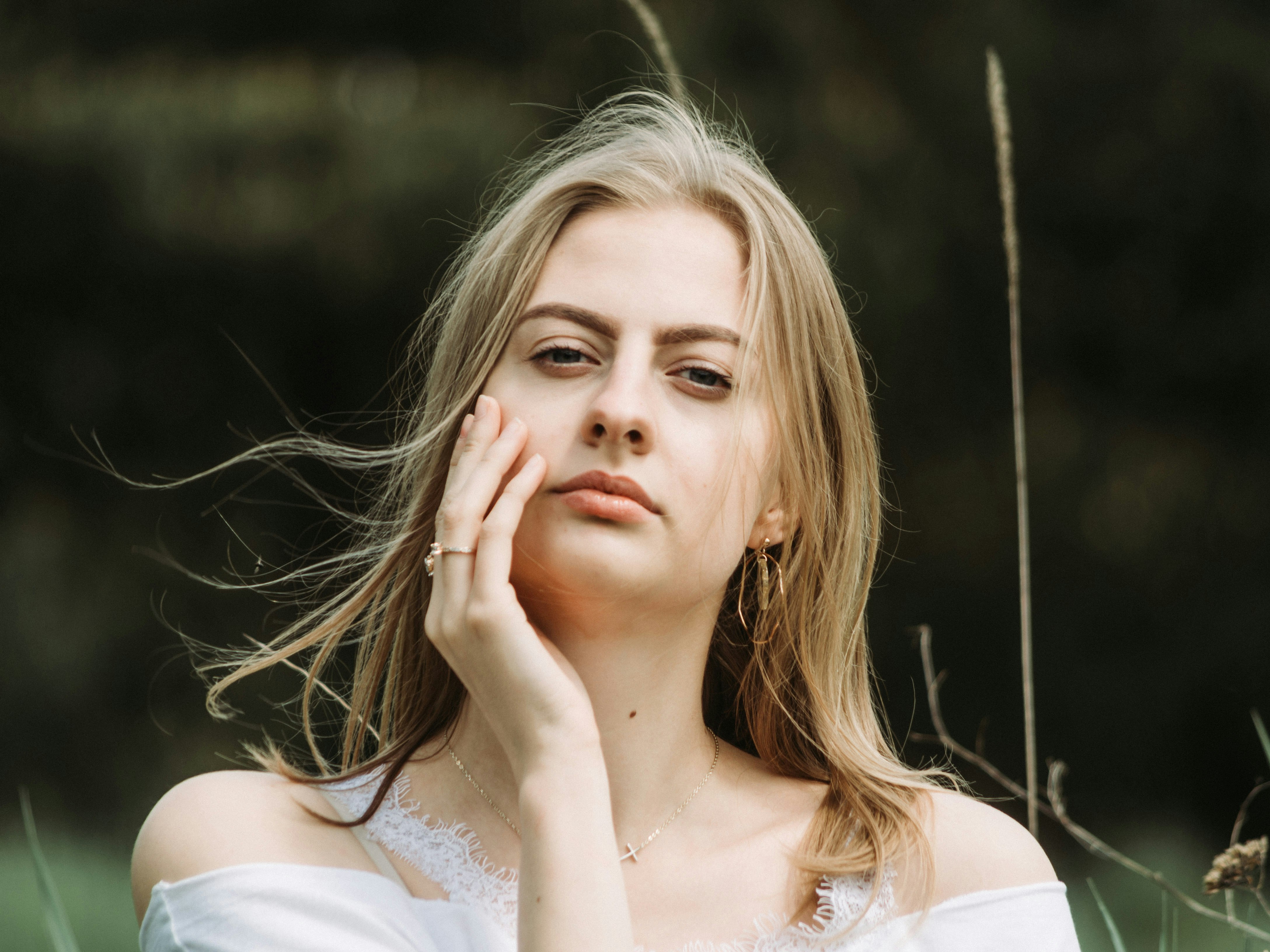 woman in white shirt with her hand on her face